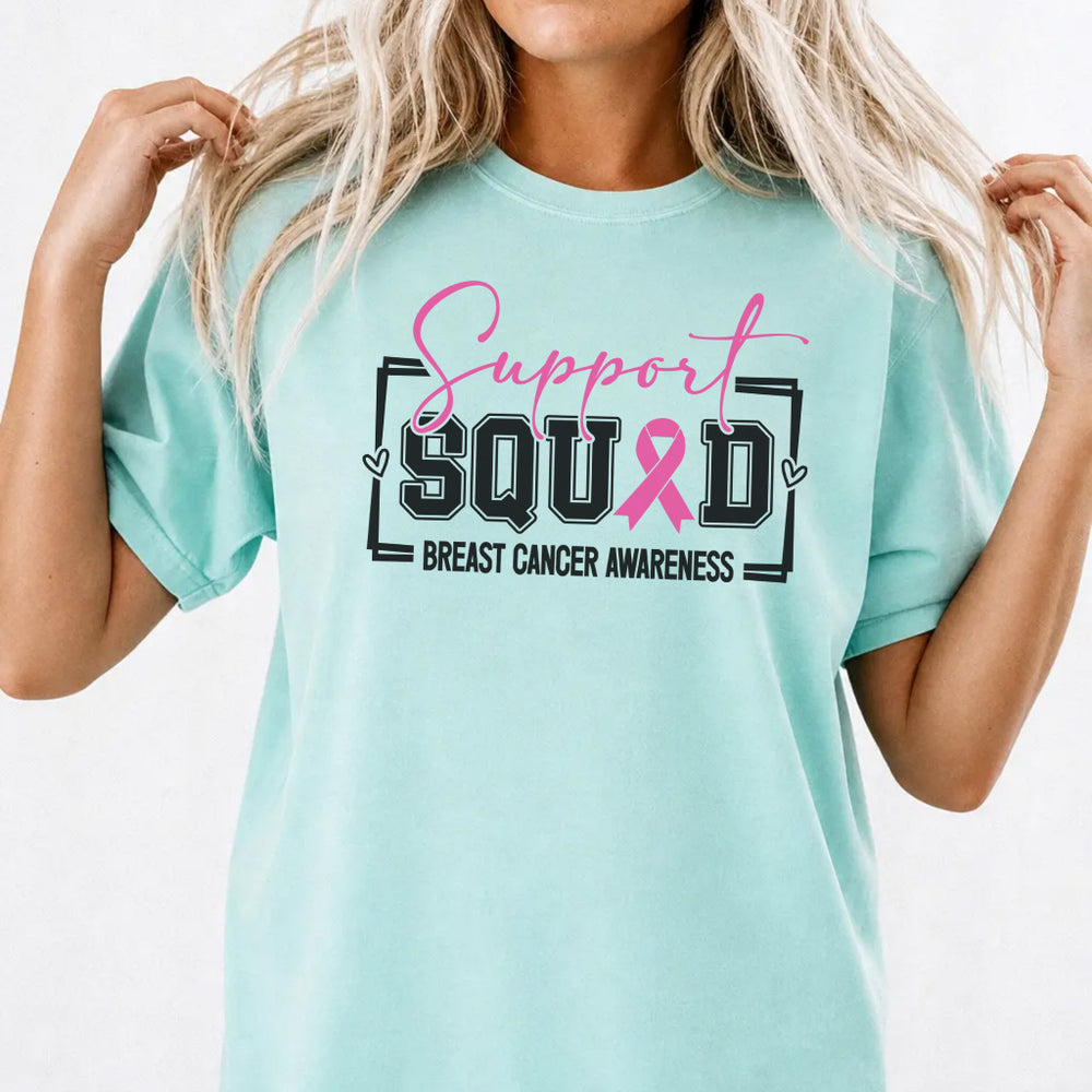 Woman wearing a chalky mint breast cancer awareness women's graphic tee with bold block lettering and pink ribbon front print