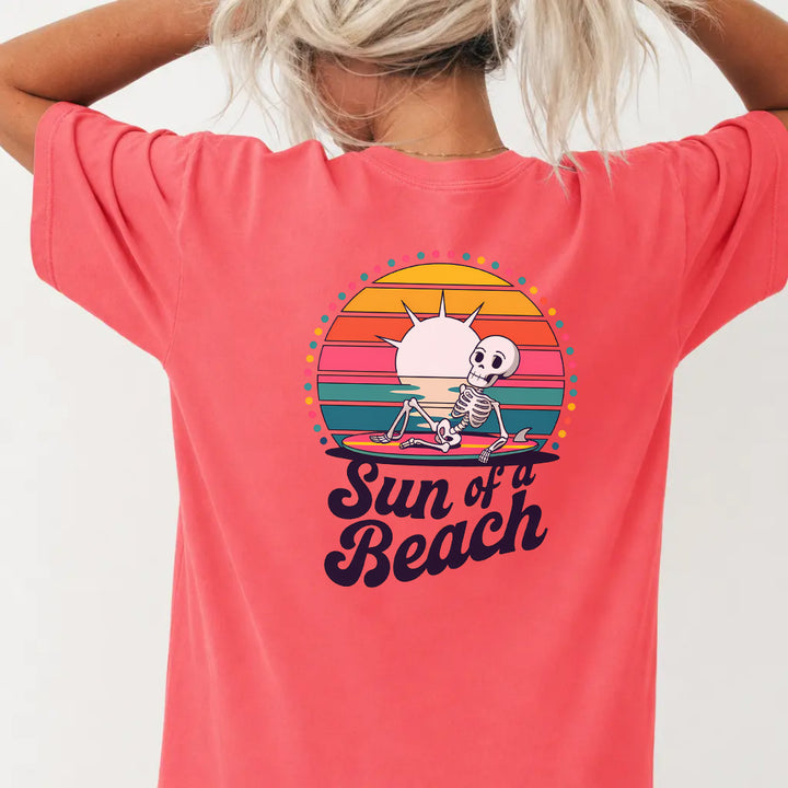 Woman wearing a watermelon red funny skeleton beach graphic tee with retro sunset back print