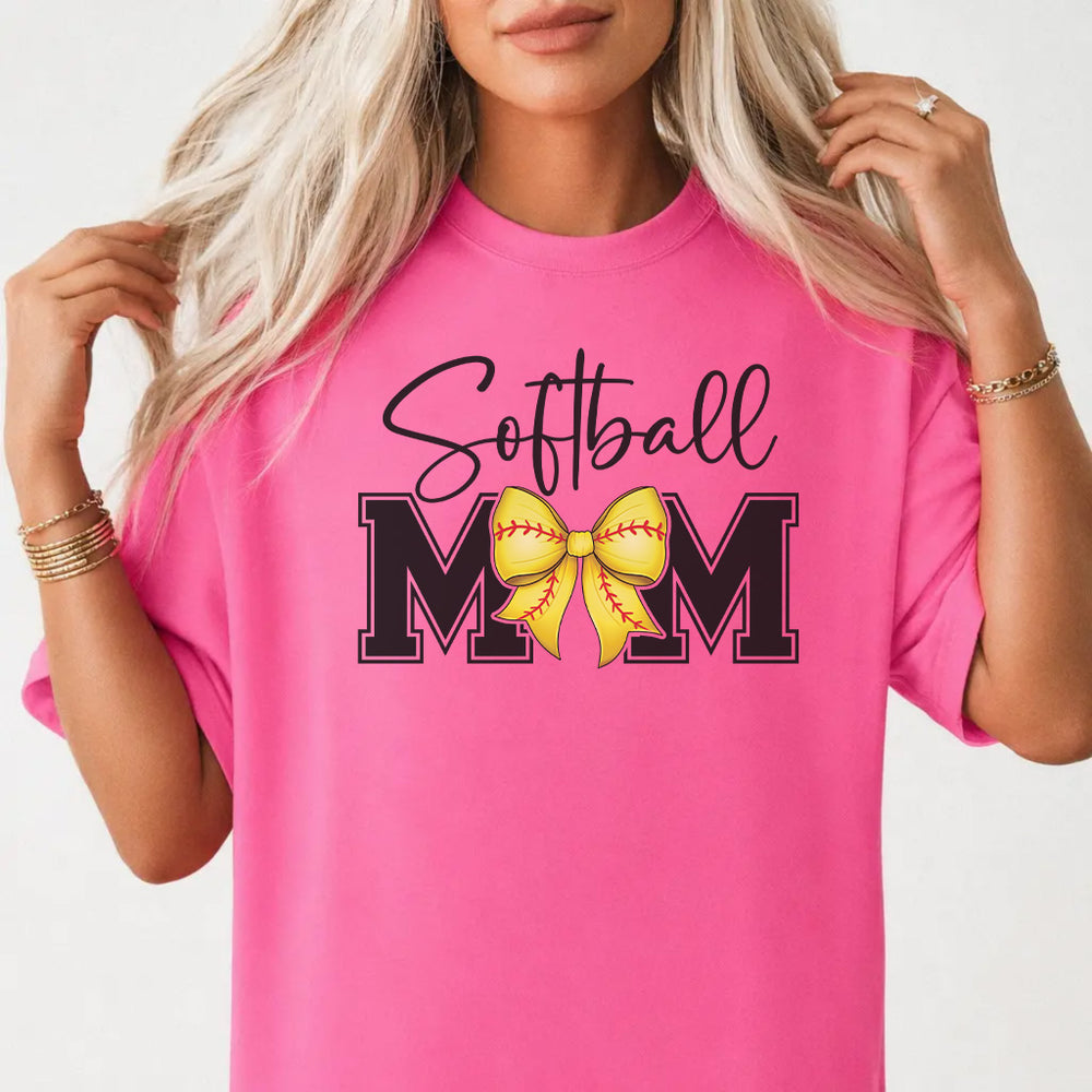 Woman wearing a neon pink softball mom bow women's graphic tee with cursive script and a yellow bow, front print