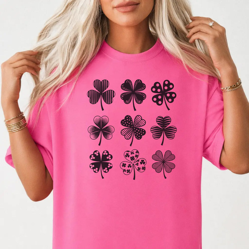 Woman wearing a neon pink St. Patrick's Day shamrock grid women's graphic tee with nine patterned clover illustrations front print