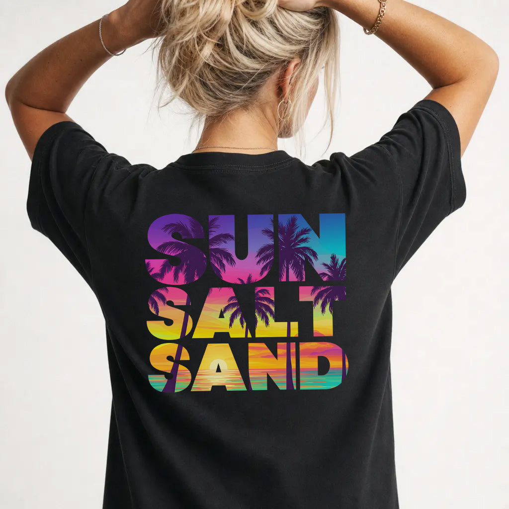 Woman wearing a black sunset beach graphic tee with colorful palm tree back print