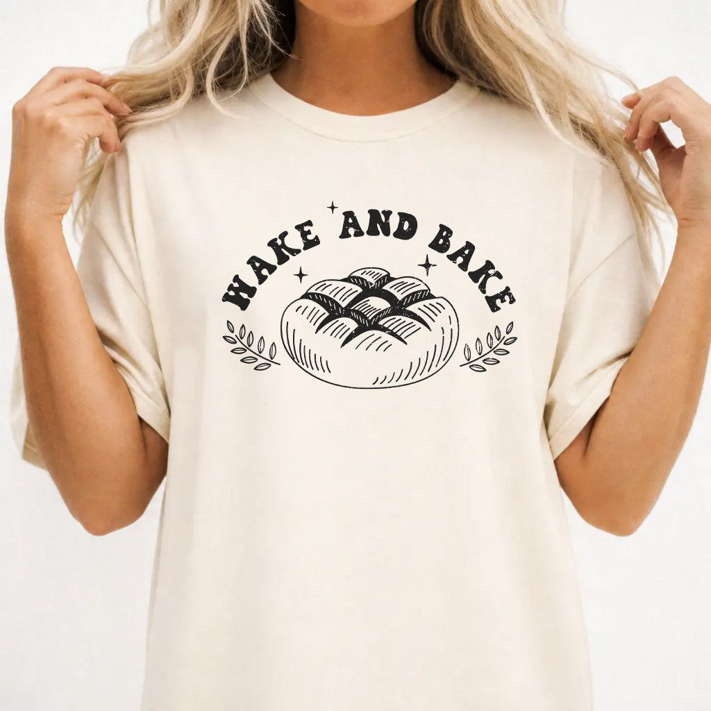 Woman wearing an ivory shirt with a rustic artisan bread loaf illustration and the phrase Wake and Bake on the front