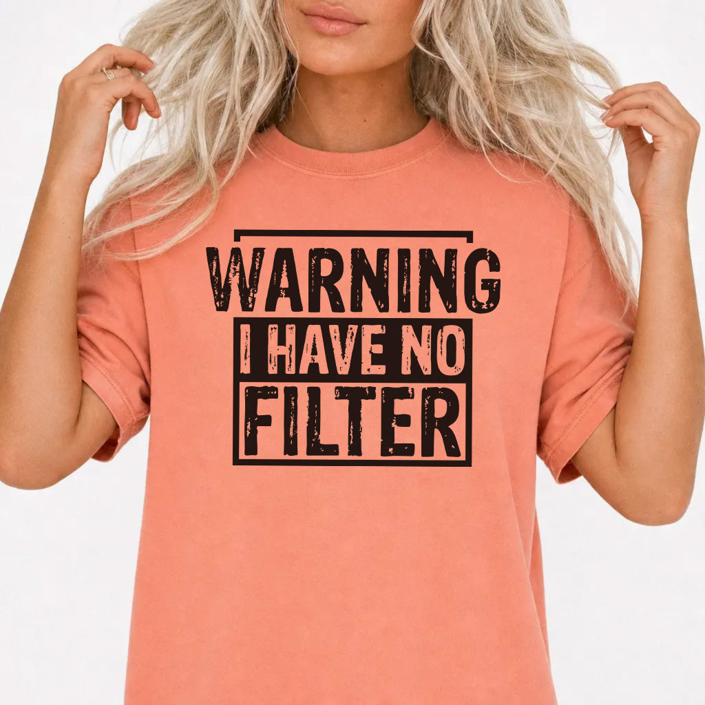 Woman wearing a terracotta shirt with bold distressed black lettering that reads Warning I Have No Filter on the front