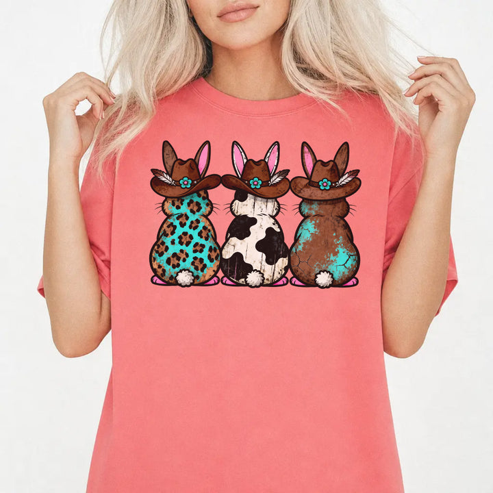 Woman wearing a watermelon shirt with three western Easter bunnies in cowboy hats featuring leopard cowhide and turquoise patterns on the front