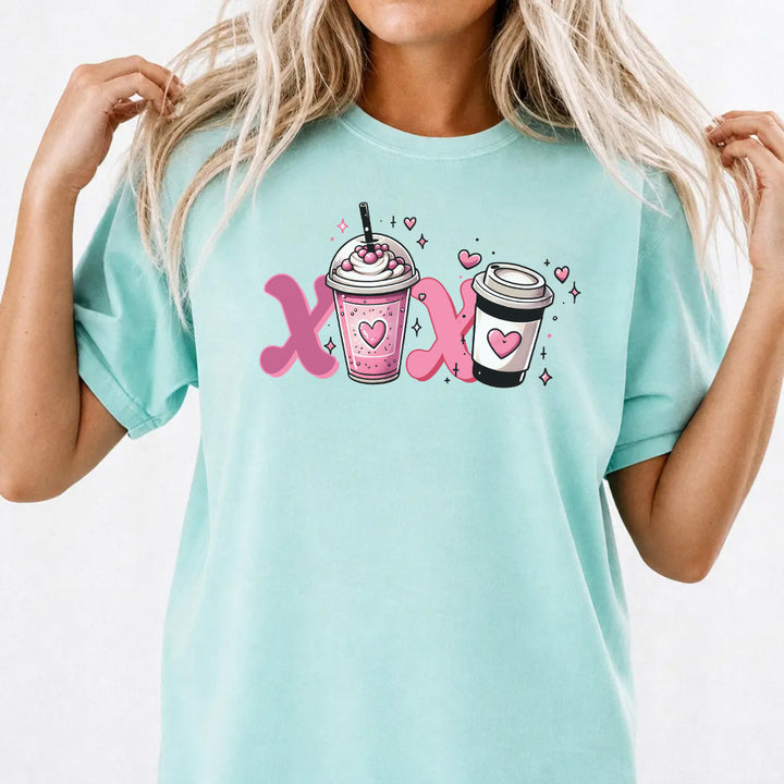 Woman wearing a chalky mint graphic tee with a pink XOXO coffee latte Valentine illustration on the front