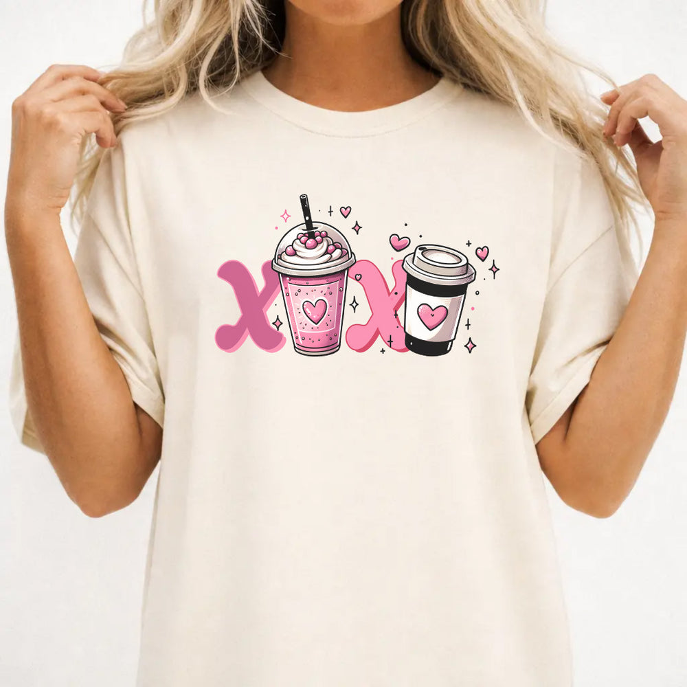 Woman wearing an ivory graphic tee with a pink XOXO coffee latte Valentine illustration on the front