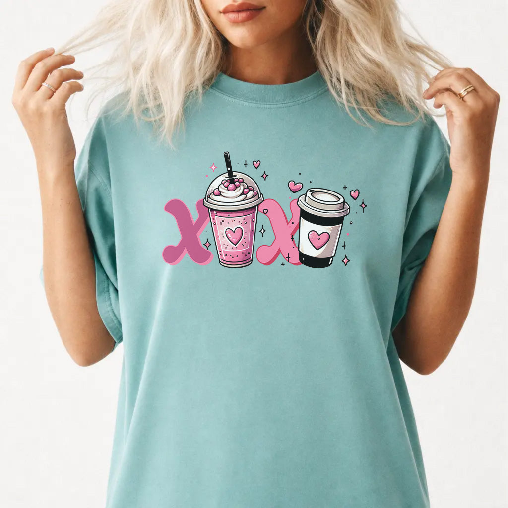 Woman wearing a seafoam graphic tee with a pink XOXO coffee latte Valentine illustration on the front