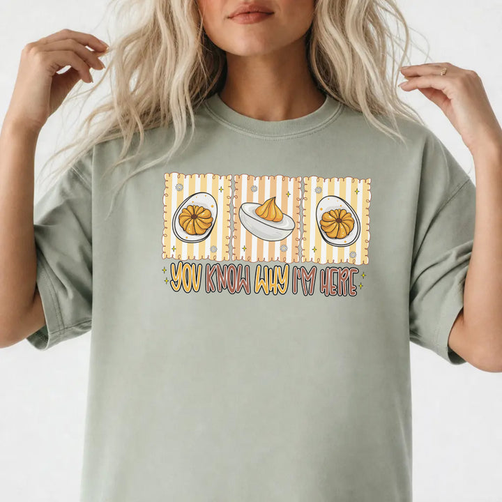 Woman wearing a bay graphic tee with a retro deviled egg illustration and the phrase You Know Why Im Here on the front