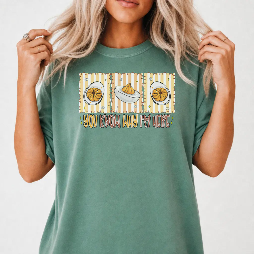 Woman wearing a light green graphic tee with a retro deviled egg illustration and the phrase You Know Why Im Here on the front