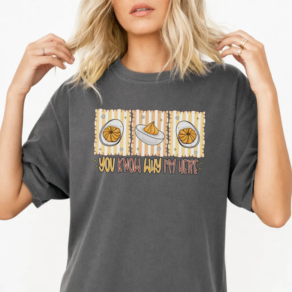 Woman wearing a pepper graphic tee with a retro deviled egg illustration and the phrase You Know Why Im Here on the front