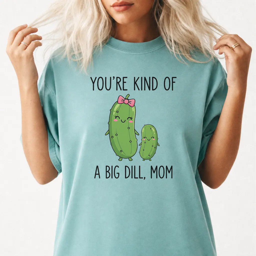 Woman wearing a seafoam graphic tee with cute pickle characters and the phrase Youre Kind of a Big Dill Mom on the front