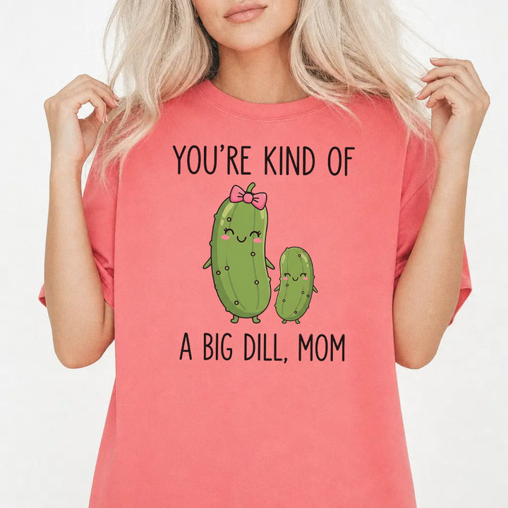Woman wearing a watermelon graphic tee with cute pickle characters and the phrase Youre Kind of a Big Dill Mom on the front